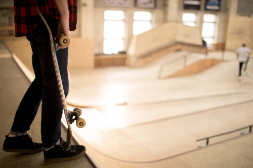 A skateboarder standing on ramp ready to do stunts in an indoor skate park.